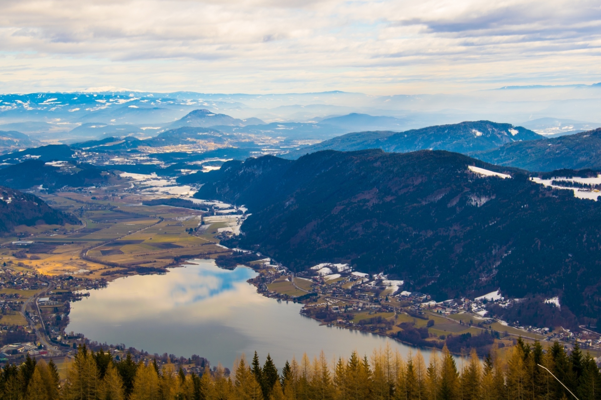 pogled na osojsko jezero iz zraka, v ozadju posamezne zaplate snega